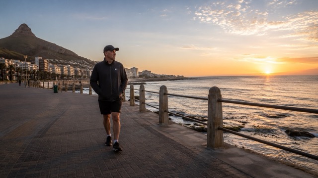Person walking on a coastal path at sunrise